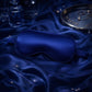 Blue satin sleep mask on a dark blue fabric background
